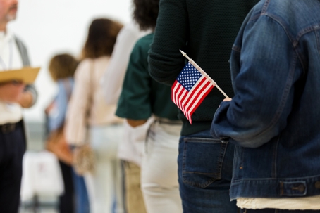 person with American flag standing in immigration line